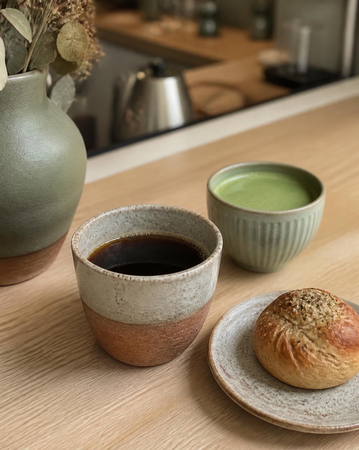 Bryggkaffe och matcha i handgjorda koppar på en träbänk